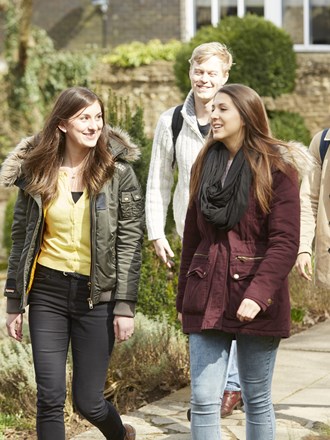A group of happy students walking through Guildford campus