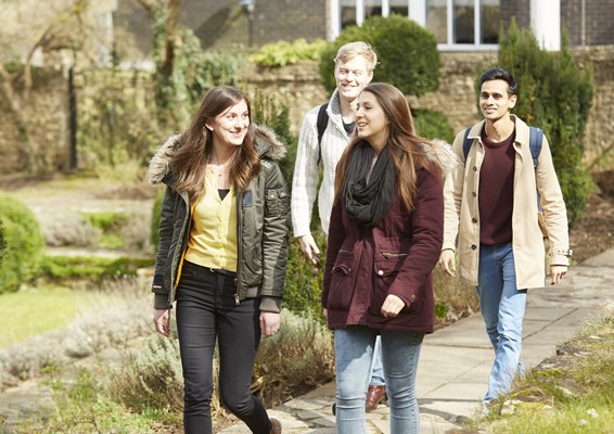 A group of happy students walking through Guildford campus
